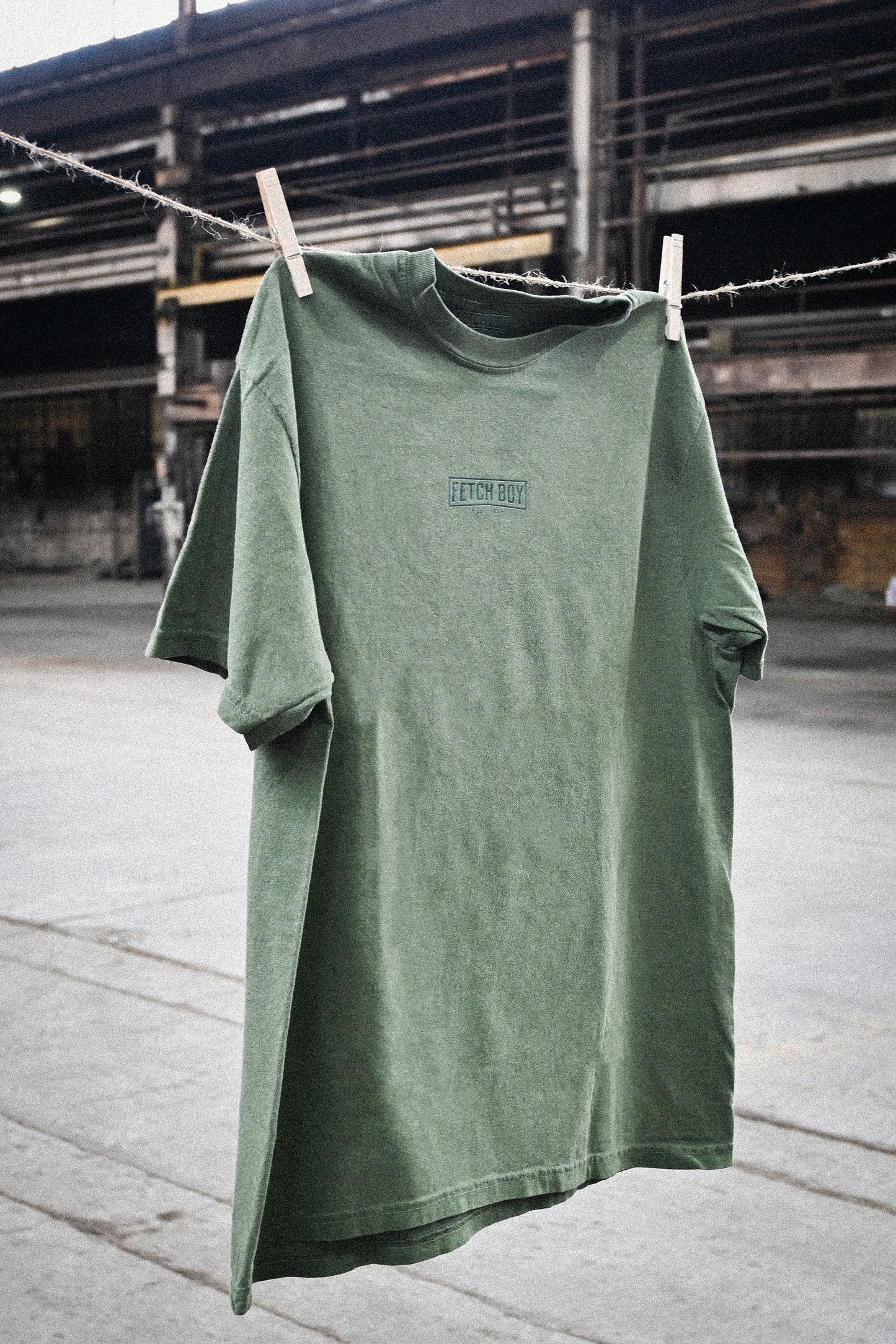 Fetch Boy Unisex Heavyweight T-Shirt in Moss in Industrial Vintage setting.