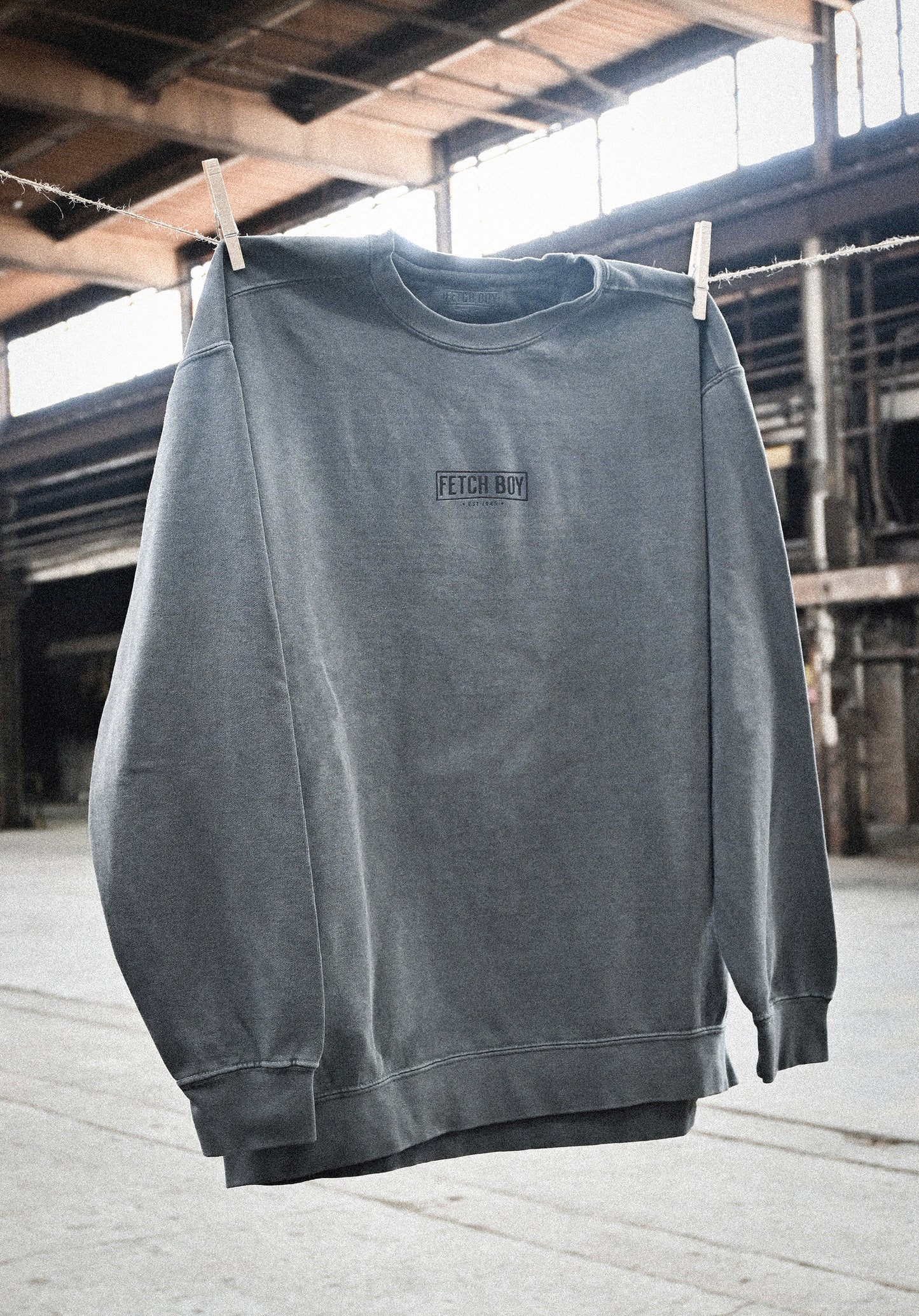 Fetch Boy Unisex Heavyweight Crewneck Sweatshirt in Steel Gray in Industrial Setting.